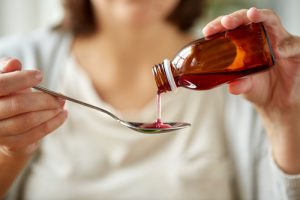Woman pouring cough medicine into spoon