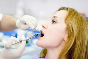 Dentist sedating patient with syringe