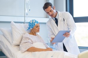 Cancer patient in bed and doctors shows them a clipboard